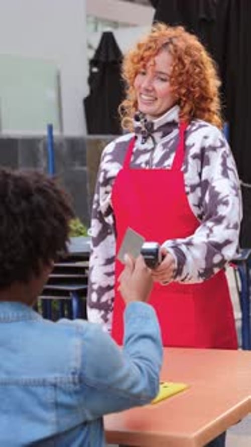 Woman accepts card from customer at counter, smiling