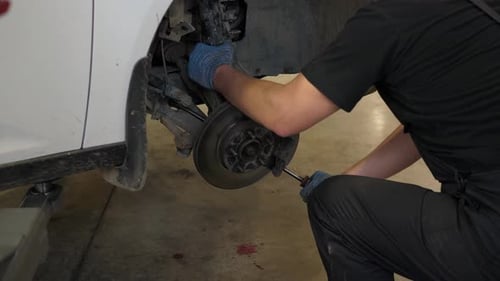 A Mechanic Repairing Car Shock Absorbers in a Car Service Station