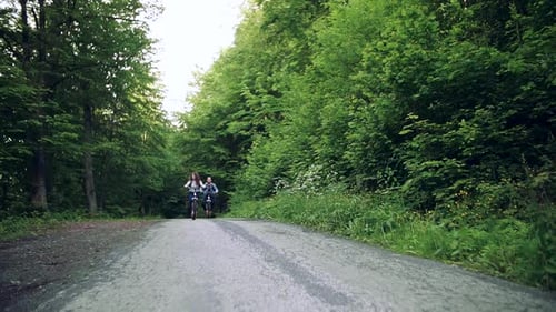 Young Adults Riding Bikes on Forest Road