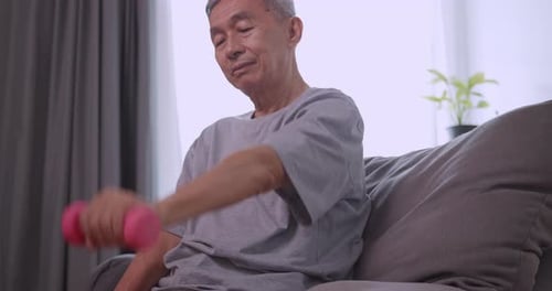 Asian old man doing exercise with dumbbells at home.