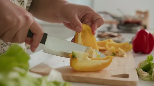 Slicing a Yellow Pepper on a Wooden Board