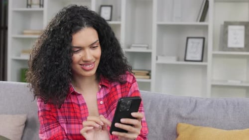 Woman Scrolling on Smartphone on Couch at Home