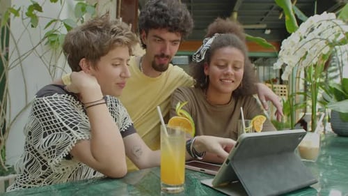 Friends Using the Internet on Tablet in Outdoor Cafe