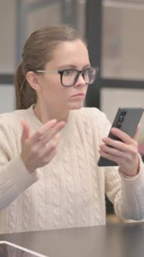 Young Woman Shocked by Loss on Phone in Office