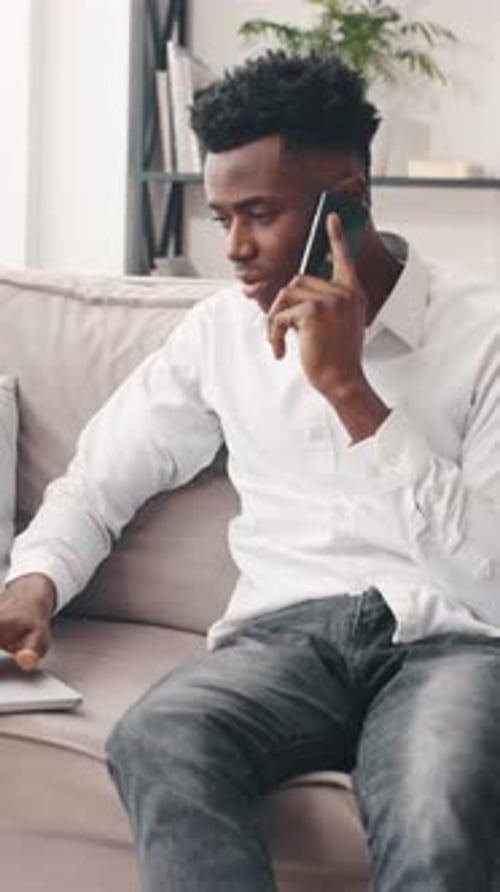 Man Using Laptop and Talking on Phone