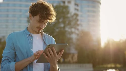 Caucasian Bearded Man Standing on the Street Surfing Internet on Tablet Computer Outdoors