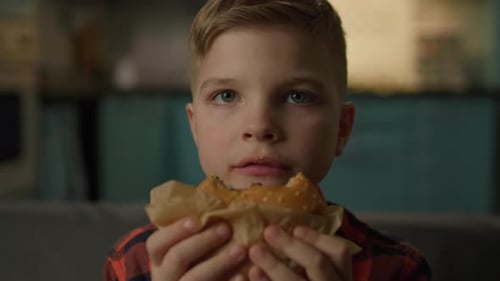 Enthusiastic Child Eats Burger Close Up Indoors