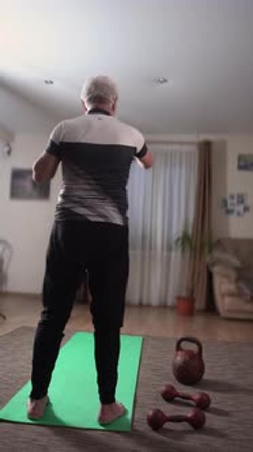 Un hombre mayor con cabello gris y barba con gafas practica golpes de karate rectos