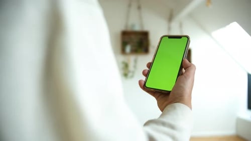 Slow motion shot of a man holding smartphone with green screen moving in white isolated background.