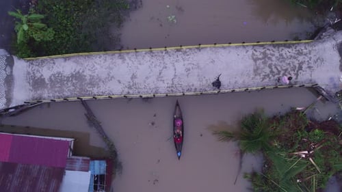 Aerial view of village on river with bridge, boats, Indonesia.
