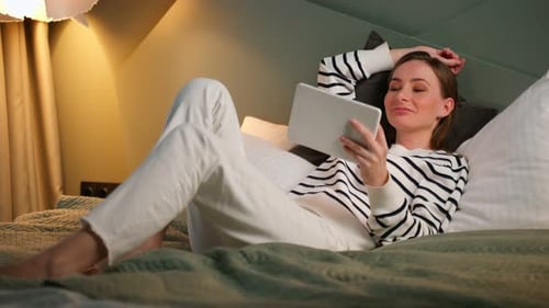 Woman Relaxing on Bed with Tablet