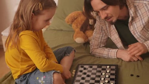Мужчина и маленькая девочка сближаются из-за шашек в уютной спальне