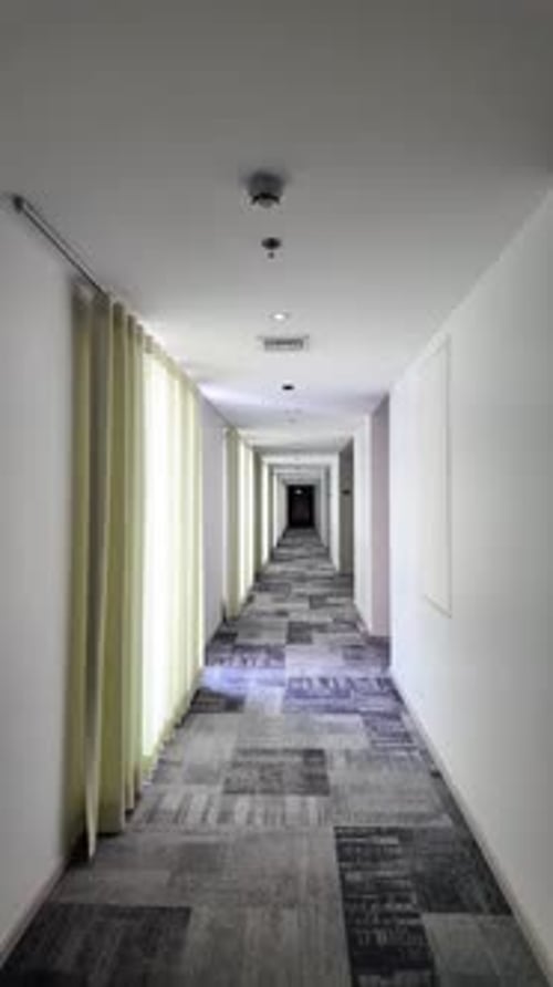Empty Hotel Corridor With Long White Walls, Curtains, And Patterned Carpet — Quiet Modern Hallway