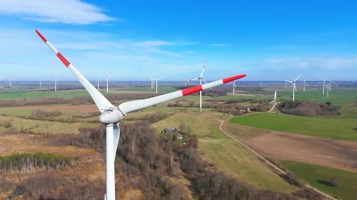 drone footage of wind turbines in a wind farm generating green electric energy on a wide green field