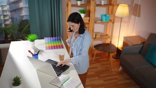 Woman Talking on Phone While Working on Laptop