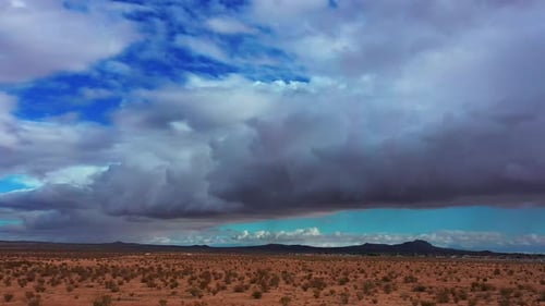 Mojave Desert basin with the distant rugged mountains on an overcast day with large cumulus clouds i