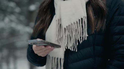 Woman Using Mobile Phone Walking in Snowy Woods