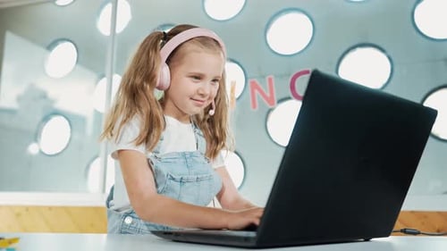 Girl wearing headset using laptop at table