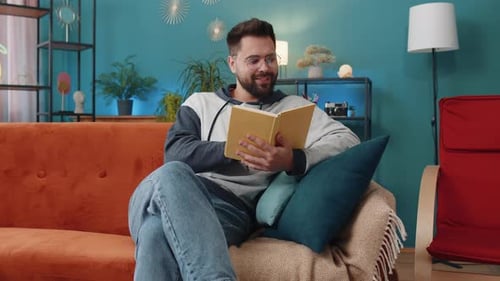 Adult Man Reads a Book on a Couch