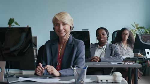 Drei interkulturelle Operatorinnen schauen im Call Center in die Kamera