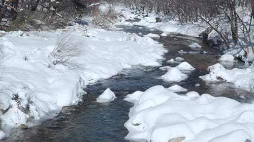 Winding Mountain River in a Snow Capped Forest in Winter - Parallax shot