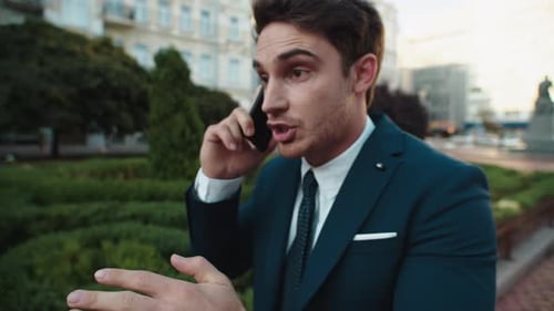 Portrait of Angry Business Man Presenting on Mobile Phone in Street. Stressed