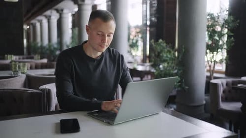 Travailleur indépendant professionnel de l'informatique travaillant à distance assis dans un café et tapant sur un clavier d'ordinateur portable