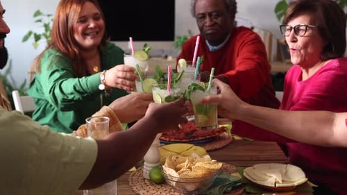 Happy friends celebrating party toasting with mojitos at cocktail bar restaurant - Young people havi