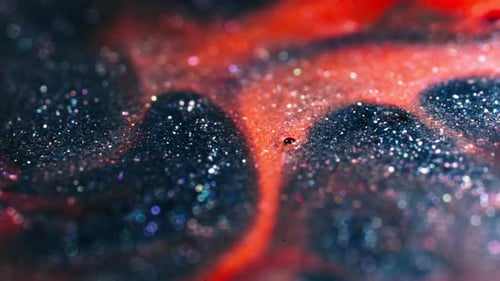 Close-up of two liquids mixing and creating abstract patterns of bubbles and swirls in motion