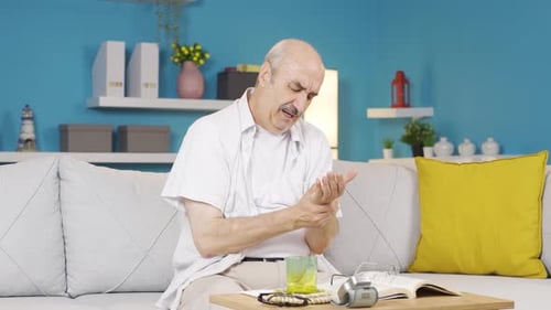 Senior Man Rubbing Wrist in Pain at Home