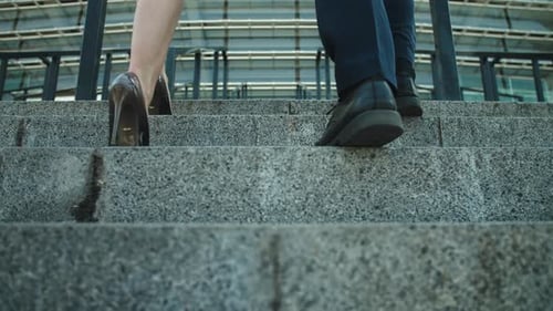 Back View Unrecognizable Business Couple Going Upstairs Outdoors. Legs Walking At Stairs In Styli...