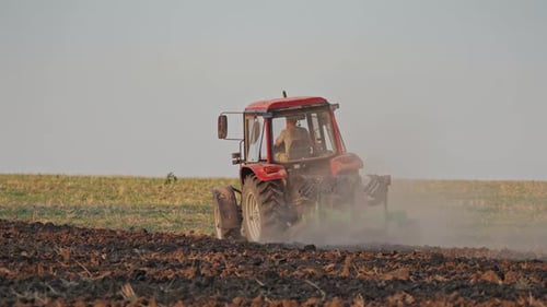 Back view of a tractor plowing the soil.