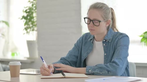 Young Woman Writing on Paper in Office