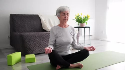 Senior Woman Meditating Indoors in Lotus Pose