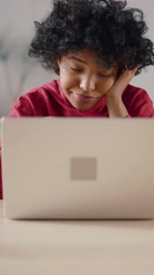 Bored African American Teenager Looking at Laptop Display During Elearning Lessons Vertical Portrait