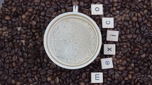 Top View of a Cup of Coffee on a Background of Coffee Beans with the Inscription Mexico