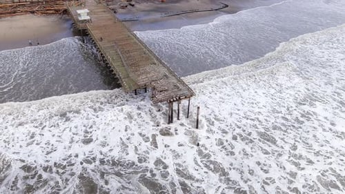 Aerial, beach pier in California destroyed by a storm caused by climate change