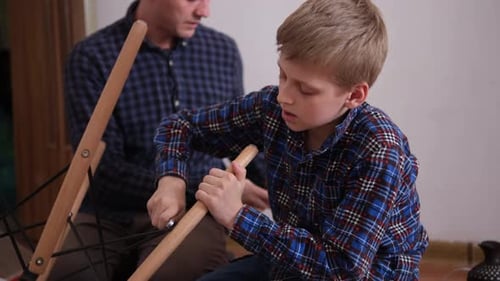 Father and Son Assemble Furniture From Small Parts Little Boy Helps His Father to Assemble a Chair