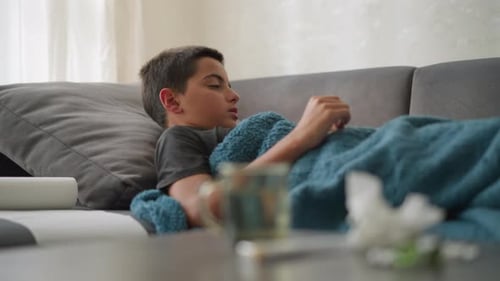 Teen Resting on Couch Under Blanket