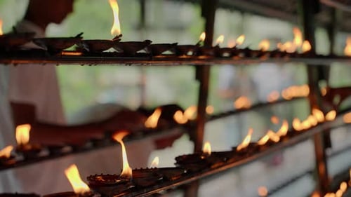 Devotees Oil Lamps at Buddhist Temple in Kandy Sri Lanka Traditional Flame Offerings in Long Rows