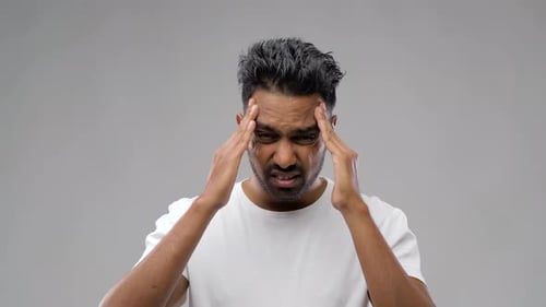 Frustrated Man Holding Temples in Studio Close-Up