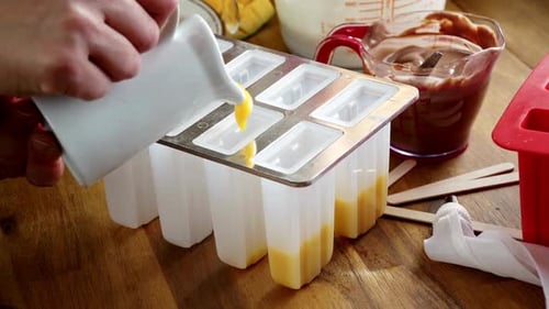 Pouring Yellow Liquid into Popsicle Molds