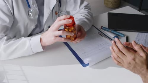 Doctor Giving Prescription Bottle to Patient