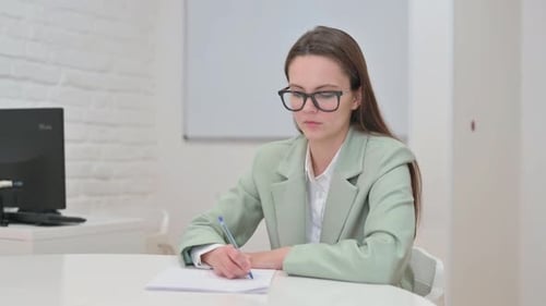 Business Woman Writing at Desk in Office