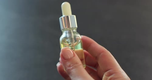 Hand holding cosmetic serum bottle
