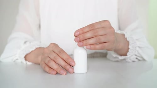 Individual Dispenses Serum from Dropper into White Bottle