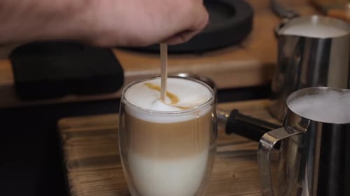 A Barista Pours Milk Into a Cup and Creates Cappuccino Art in a Coffee Shop