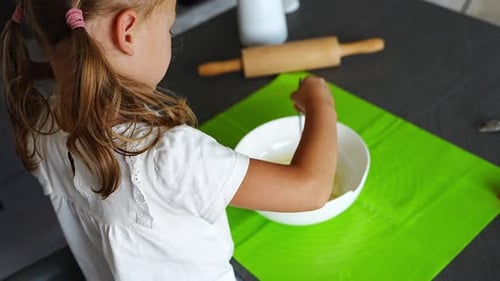 Child Mixes Ingredients in Bowl at Home