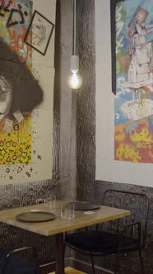 Slow Pan of Colorful Clown Artwork on Wall By Empty Restaurant Table
