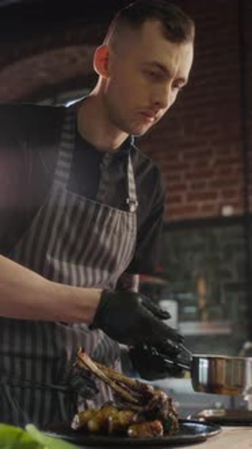 Chef Dresses Prepared Dish with Sauce in Kitchen